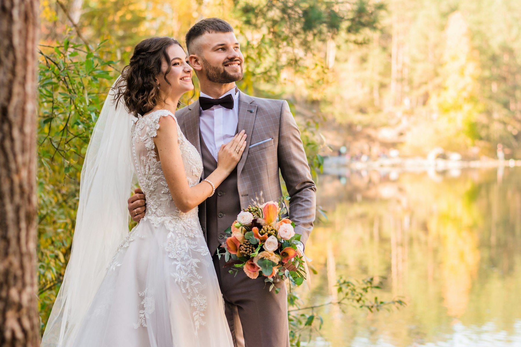 A couple embracing by a lake surrounded by autumn trees