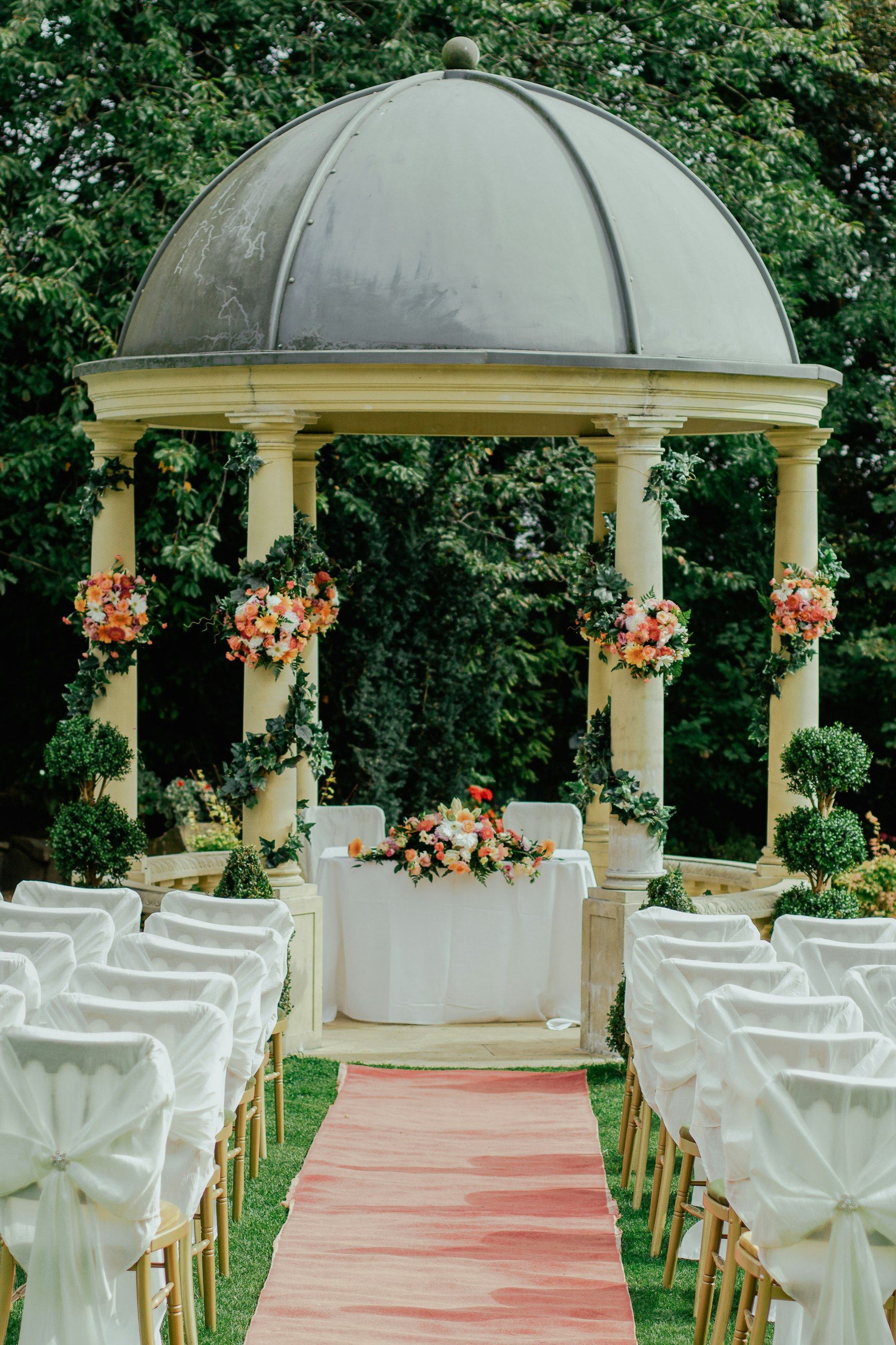 A garden gazebo hung with flower garlands above a set table