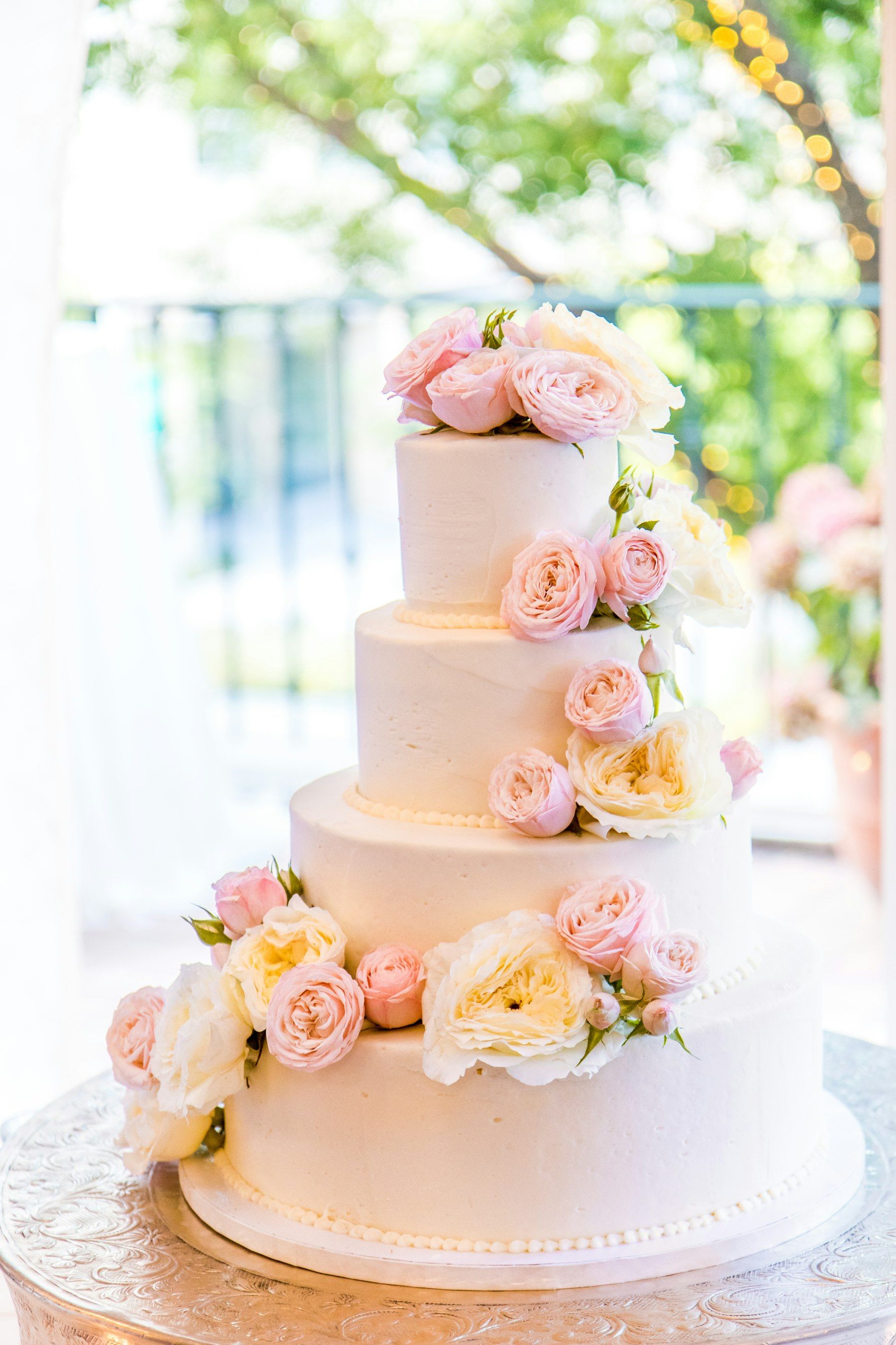 A three-tier white wedding cake decorated with pink roses